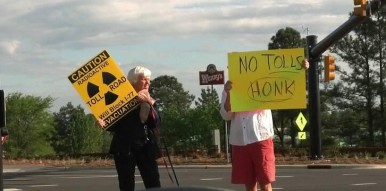 Anti-toll protesters held signs at Exit 28 in Cornelius in May 2015. (Lyndsay Kibiloski / CorneliusNews.net)