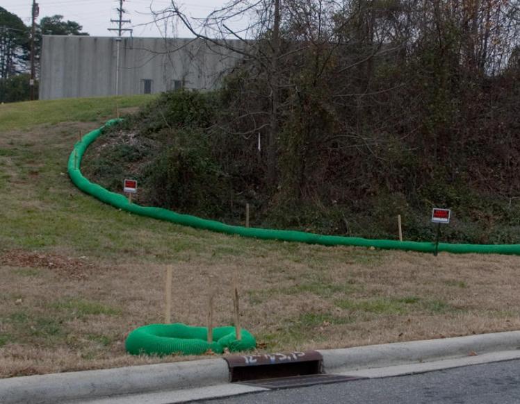 Green "filter socks" are designed to control runoff behind the old Carolina Asbestos plant in Davidson. The trees will be removed and the hill full of asbestos covered starting next week. (David Boraks/WFAE)